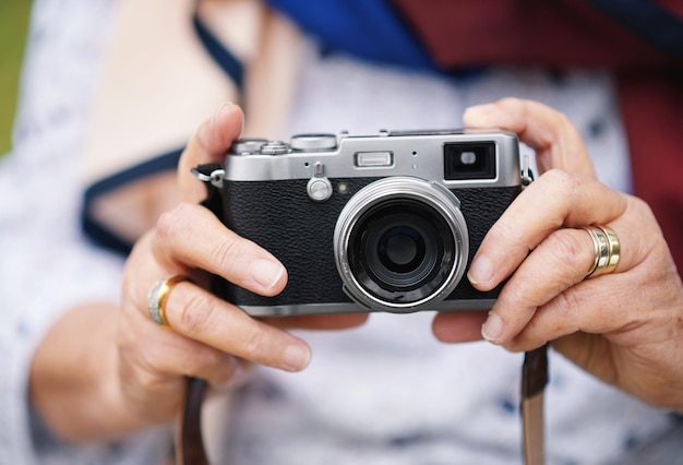 Fotografia con fotocamera retrò e viaggi con le mani di una donna anziana che scatta foto durante il viaggio esplorando e in un'avventura primo piano del fotografo di vacanze in pensione e ricordi in vacanza