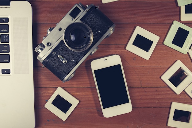 Retro camera and some old photos on wooden table.