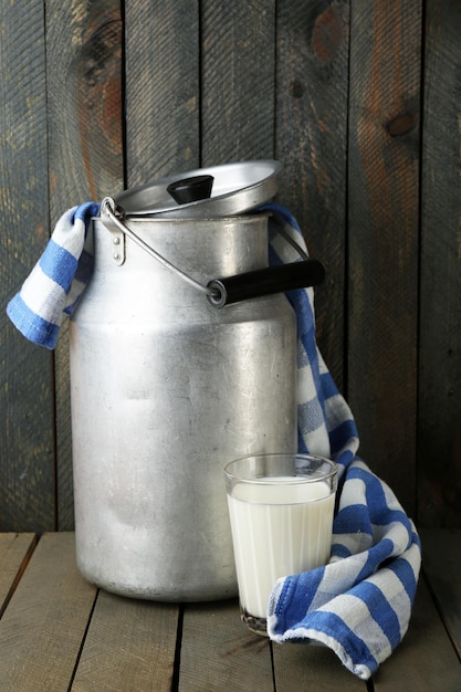 Retro can for milk with colorful towel on color wooden background