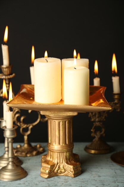 Retro candlesticks with candles on wooden table on black background