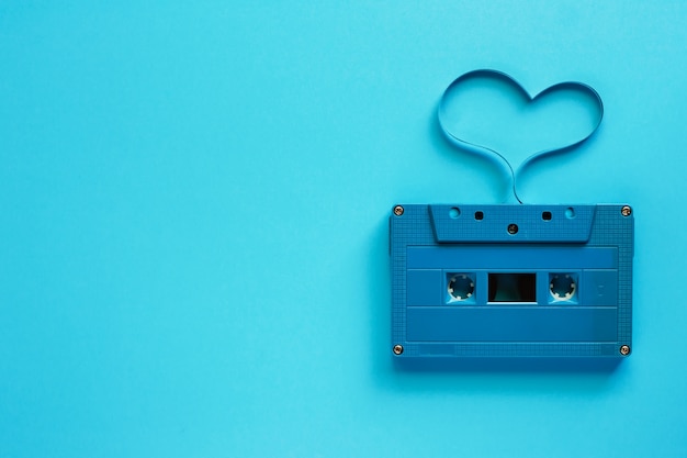 音楽と愛のコンセプトのための青い背景にハート型のレトロなカセットテープ