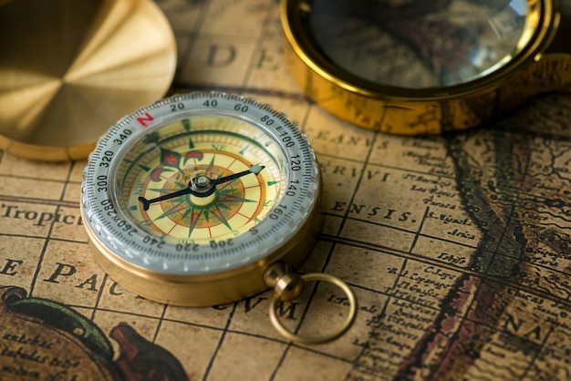 Retro compass with old map and magnifier closeup