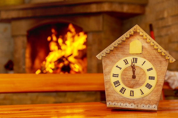 Retro cuckoo clock with roman numerals on the background of a\
fireplace with fire. on the clock face 12 hours without 5\
minutes.