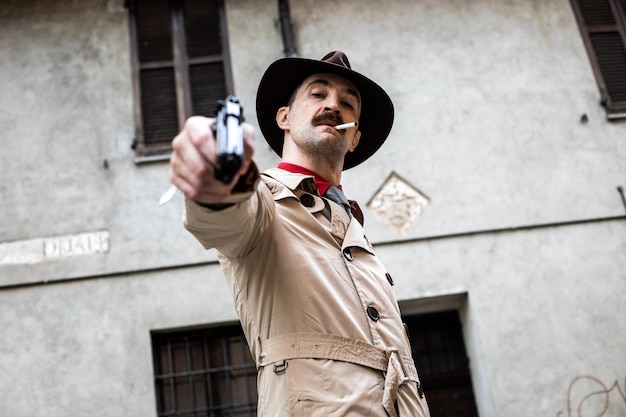 Photo retro detective posing with gun on urban background