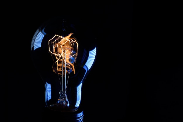 Retro Edison lamp with incandescent tungsten filament close-up on a black background