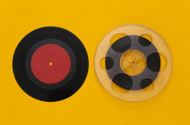 Retro flat lay. Audio magnetic tape reel and vinyl plate on yellow