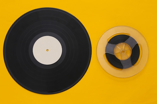 Retro flat lay. Audio magnetic tape reel and vinyl plate on yellow