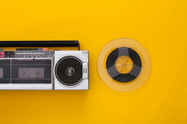 Retro flat lay. Retro portable stereo cassette recorder and audio magnetic tape reel on yellow