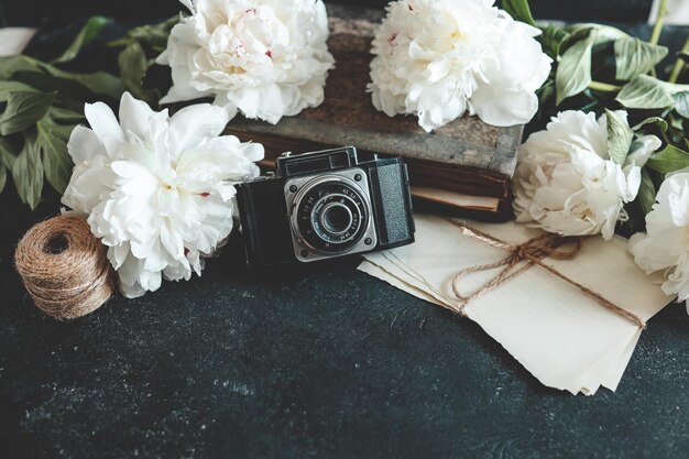 retro fotocamera met boek en verse pioenbloemen