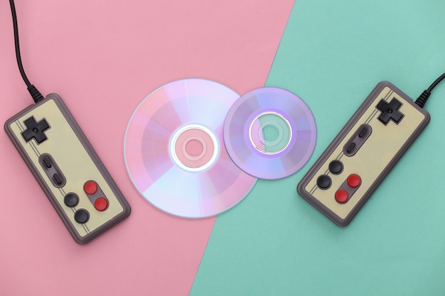 Retro gamepad en cd's op blauw roze achtergrond. Gaming, videogamecompetitie. Bovenaanzicht