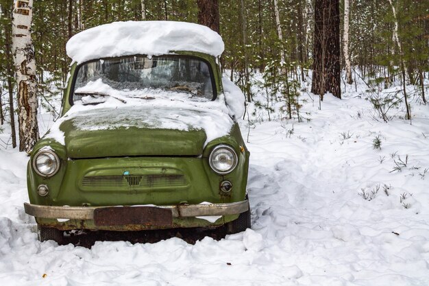 Retro green car stands in the winter forest