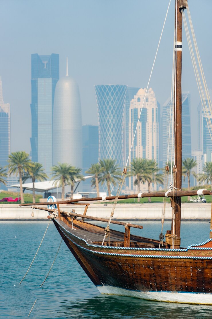 Photo retro historical boat with blurred panoramic view of modern skyline of doha and green palms on surface