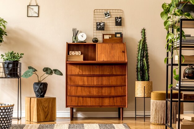 Foto retro interieur van woonkamer met houten vintage bureau, plank, gouden poef, kubus, planten, cactussen, boeken.