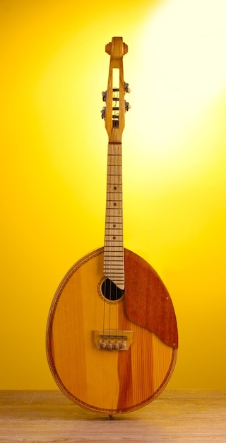 Retro kobza ukrainian musical instrument on wooden table on yellow background