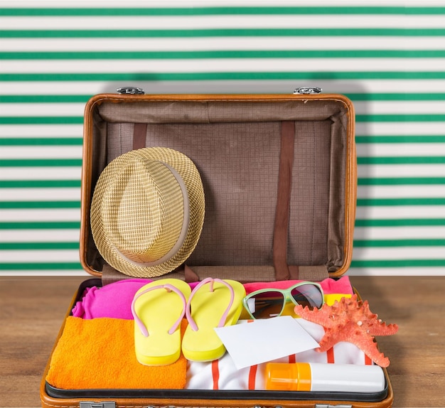 Retro koffer met reisobjecten op strand achtergrond