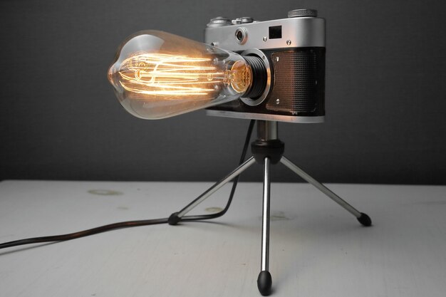 Ретро лампа из старого фотоаппарата с лампой эдисона на сером фоне.