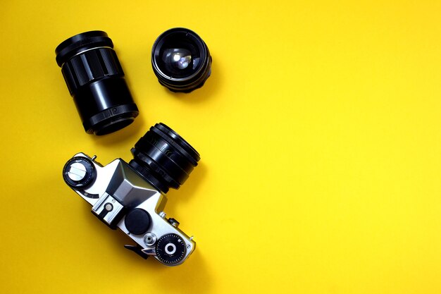 Retro lenses and camera lie on a yellow background.