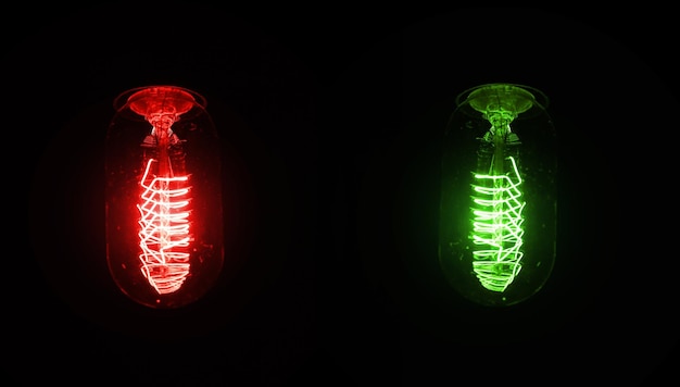 Retro looking light bulb glowing on dark background, bright wire visible in glass - red and green version, but colour can be changed with hue / saturation tool