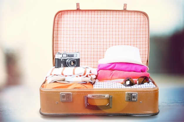 Photo retro luggage with colorful clothes on blurred background