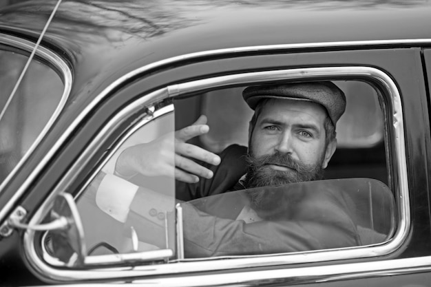 Retro man in retro car showing communicative gesture