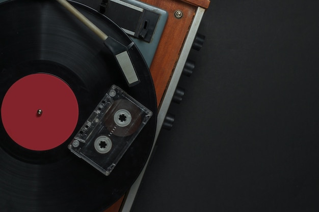 Retro music concept. vinyl record player with a vinyl record,
audio cassette on black background. 80s. top view