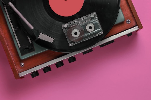 Retro muziek concept Vinyl platenspeler met een vinyl record audiocassette op roze achtergrond 80s bovenaanzicht