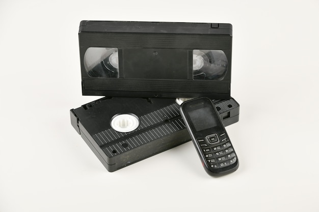 Retro objects on a white background. push-button telephone and video cassette. Analog media technology of the past. Copy space