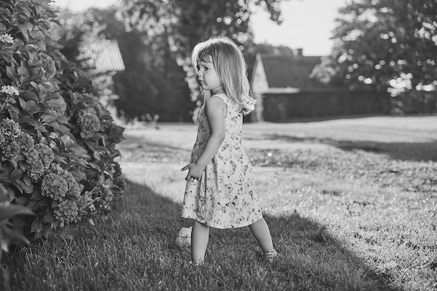 Retro photo of a sad child in a sundress in the suburbs