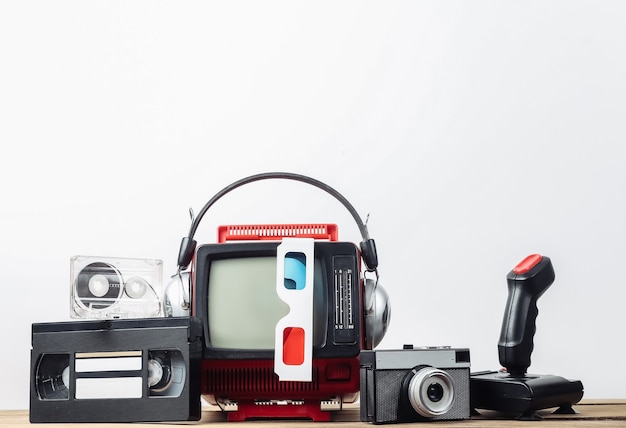 흰색 배경에 헤드폰, 3d 안경, 카메라, 조이스틱, 오디오 및 비디오 카세트가 있는 복고풍 휴대용 미니 TV. 80년대, 레트로 스타일의 속성