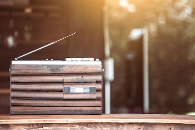 Photo retro radio cassette stereo on wooden table in vintage color tone