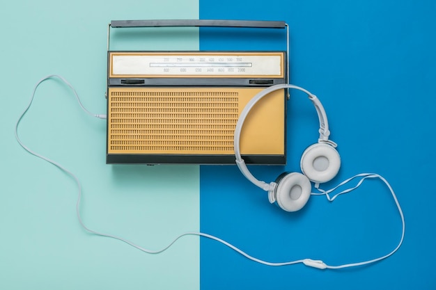 Retro radio and white headphones on a twotone background Vintage technique