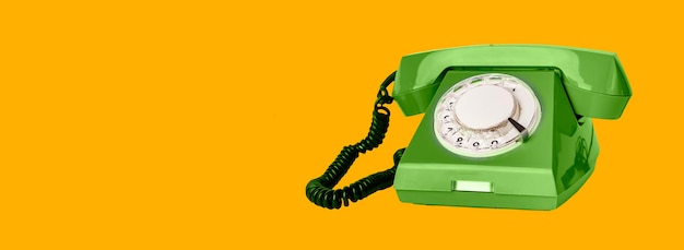 Retro rotary green phone with cord on orange ad banner background with copy space for text