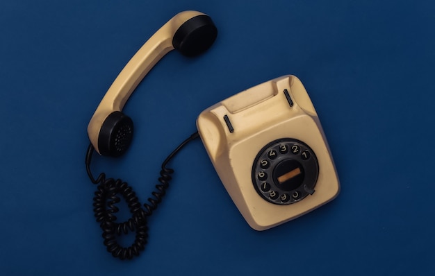 Retro rotary phone on classic blue background. Color 2020.