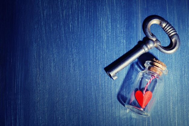 Retro sleutel met rood hart in kleine glazen fles op een houten tafel achtergrond kleur