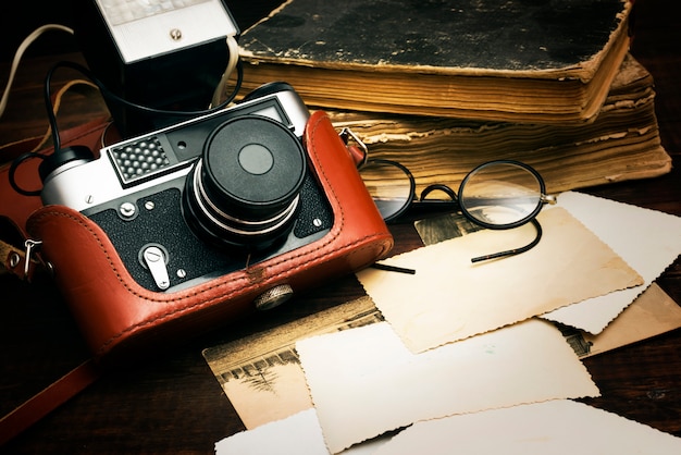 retro still camera and some old photos on wooden table background