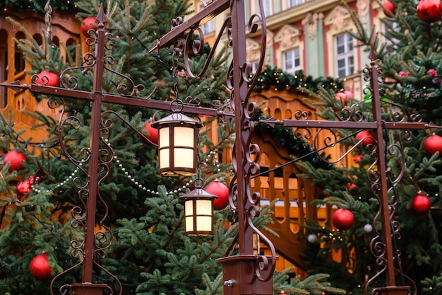 Retro street lanterns and red christmas balls with LED garlands on decorated natural New Year trees on a festive Christmas fair on central city street.