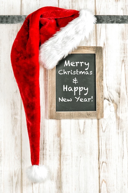 Retro style christmas decoration. Red Santa hat and vintage chalkboard. Merry Christmas Happy New Year