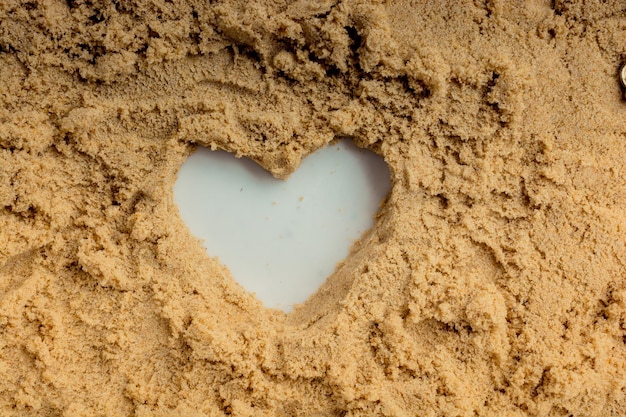 Retro style key and a heart shape on brown sand