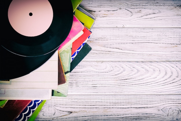 Retro styled image of a collection of old vinyl record lp's with sleeves on a wooden background with Copy space top view toned