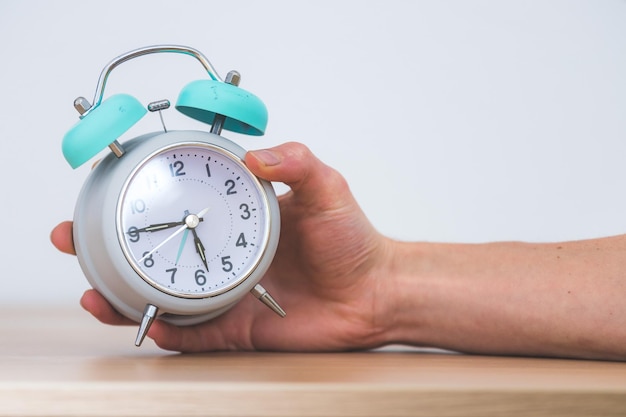 Retro styled white alarm clock in man's hand isolated