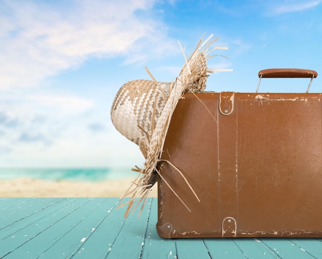 Retro suitcase with travel hat on tropical beach background