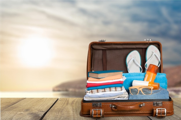 Retro suitcase with travel objects on beach background