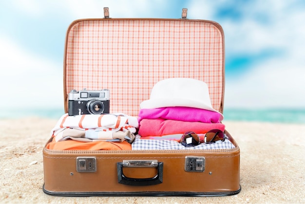 retro suitcase with travel objects on beach background