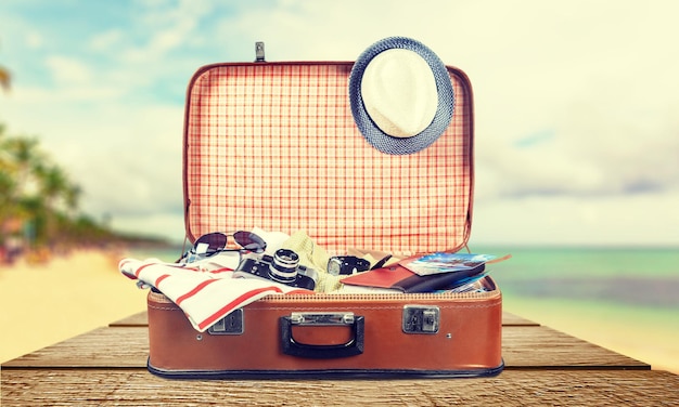 Retro suitcase with travel objects on light background