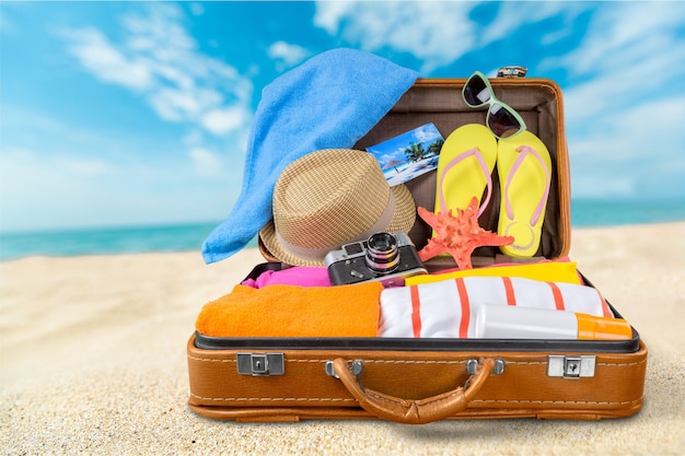 Retro suitcase with travel objects  on sea background