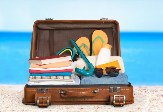 Retro suitcase with travel objects  on sea background