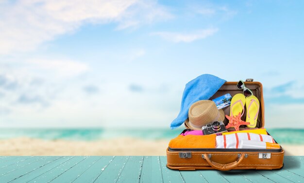 Foto valigia retrò con oggetti da viaggio sullo sfondo del mare