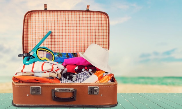 Retro suitcase with travel objects on wooden board on natural background