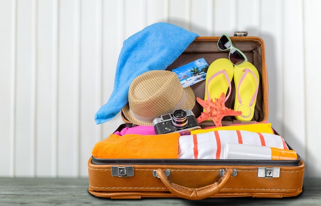 Retro suitcase with travel objects on wooden board on natural background