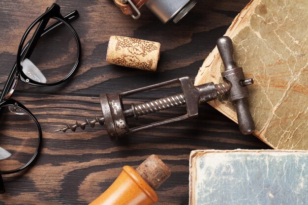 Retro table with vintage items Old books glasses camera wine bottle and corkscrew Top view